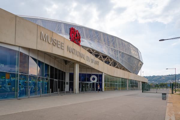 La façade du Musée national du sport, avec son toit à l’architecture particulière et une grande sculpture rouge.