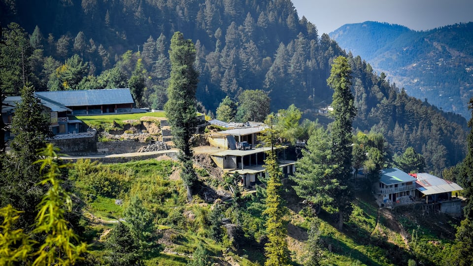 A mountainous landscape with several buildings nestled among trees.