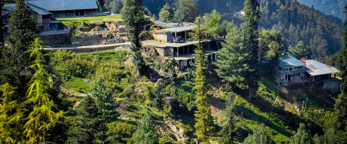 A mountainous landscape with several buildings nestled among trees.