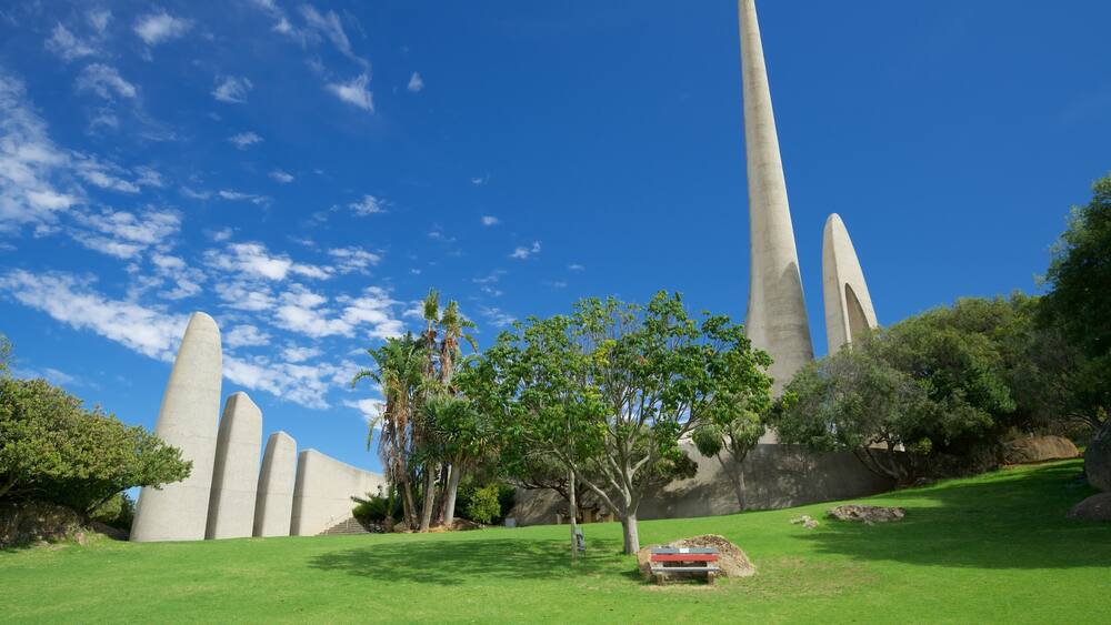 A monument with tall, slender columns and a grassy area with trees.