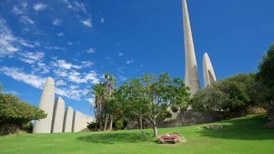 Un monumento con columnas altas y esbeltas, y un área verde con árboles.