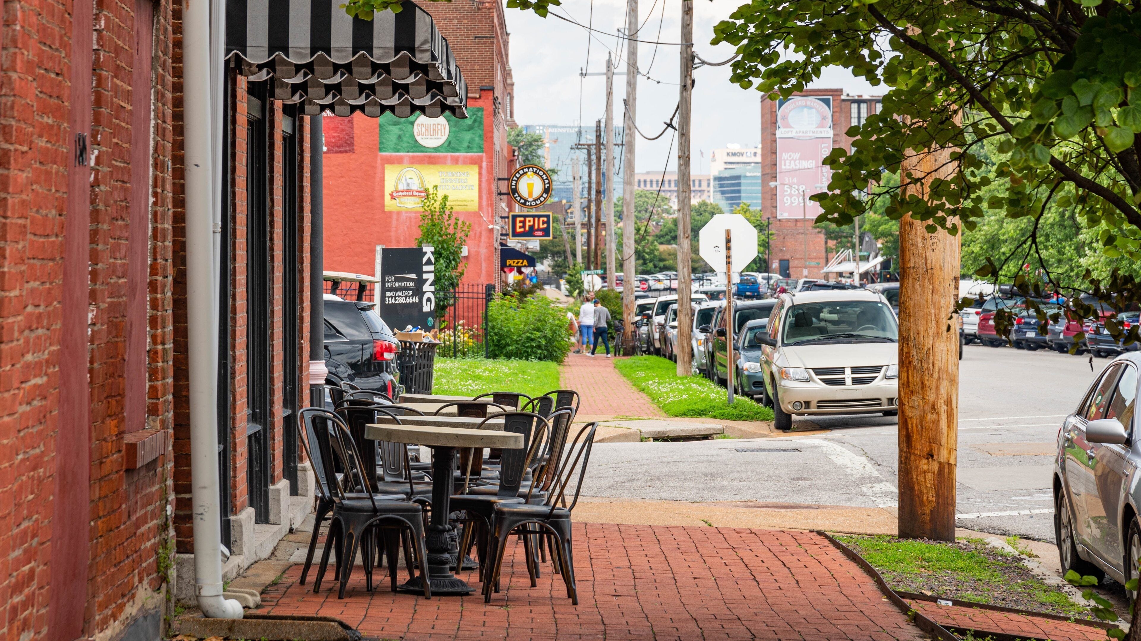 A brick building with a black awning, outdoor seating, and a sign for 'King Pizza'.