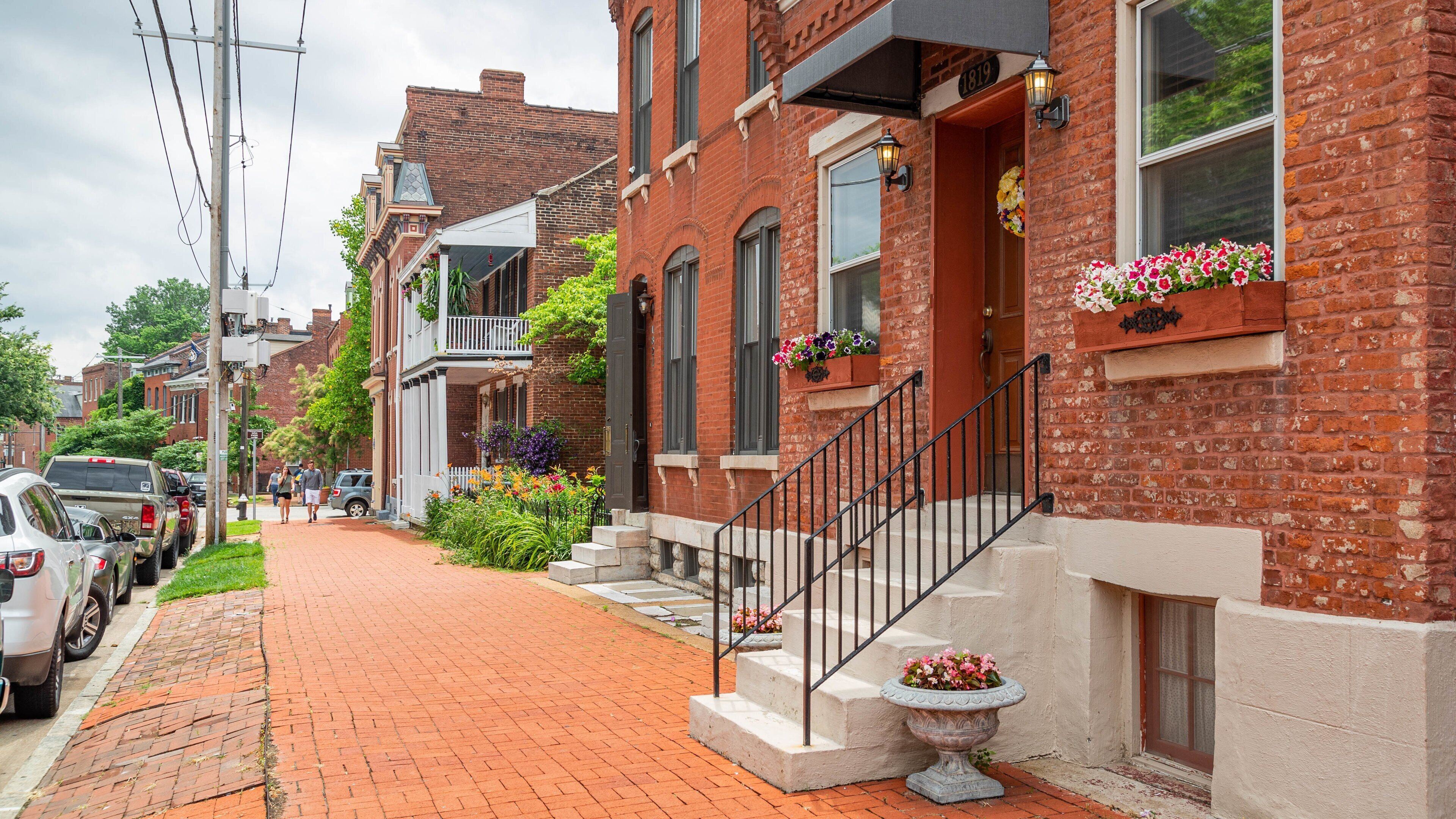 A brick row house with a front porch, a flower box, and a mailbox.
