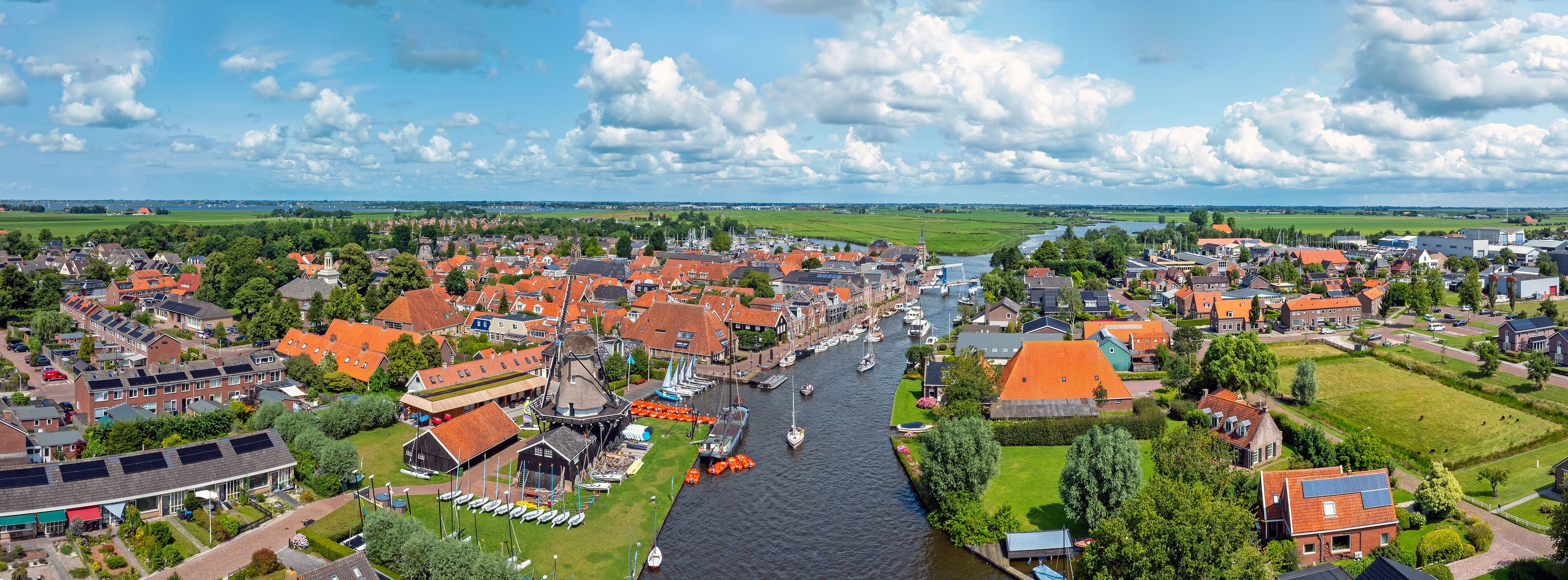 A riverside town with red-roofed houses, a canal, and boats.