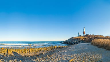 A rocky beach with a lighthouse on a hill.