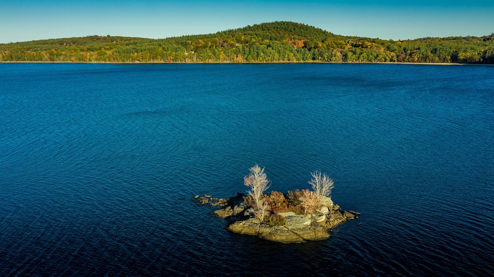 A large body of water with a small rocky island in the center.