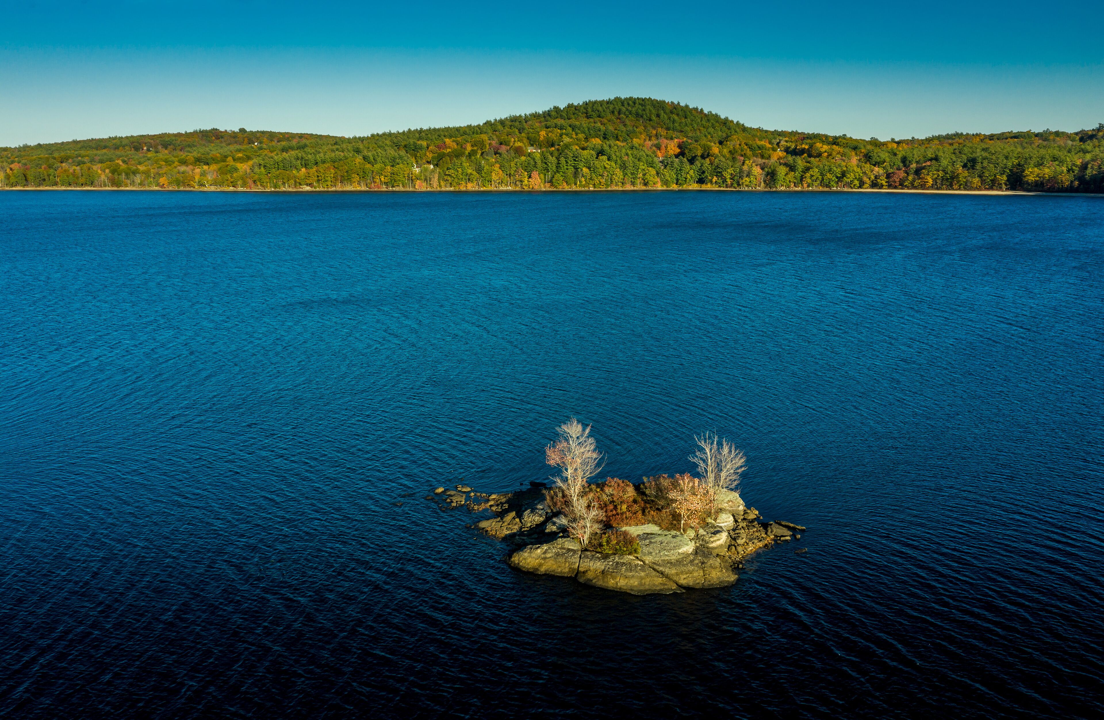 A large body of water with a small rocky island in the center.