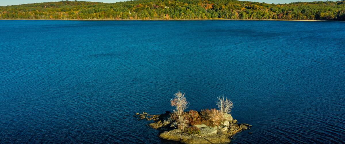 A large body of water with a small rocky island in the center.