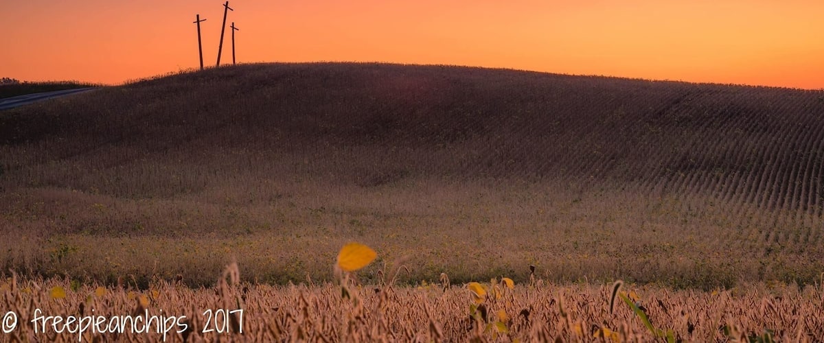 A sunset over a hilly landscape with three crosses on a hill.