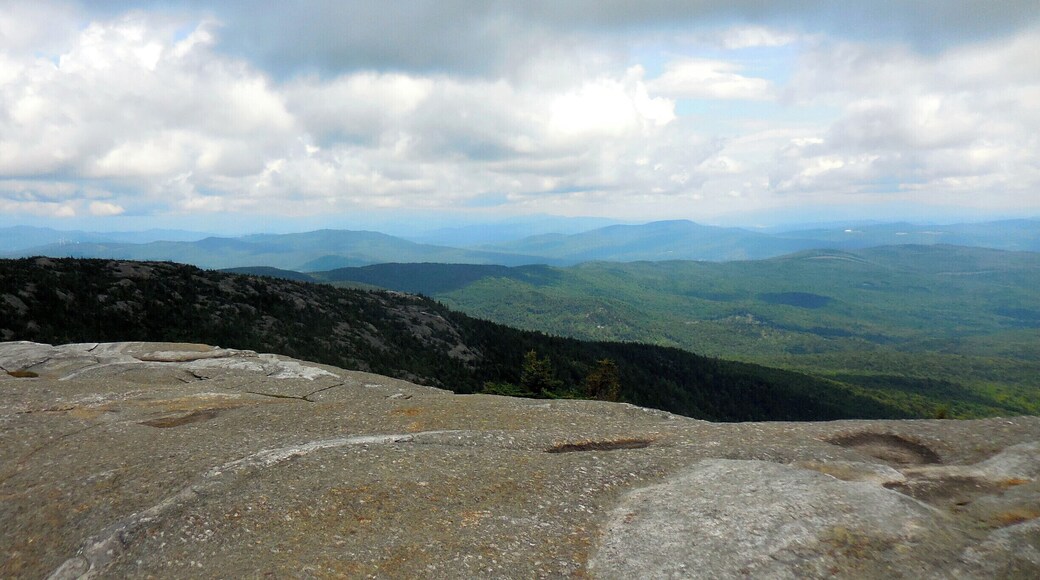 At the summit of Mt. Cardigan. A 3121 ft peak in Central New Hampshire. A moderate hike of 1.5 miles from the parking lot on the western side of the mountain. Stunning 360 degree views off of the granite, treeless summit make this an outstanding short day hike for families. It can be warm hiking up, and quite cooler with a lot a wind at the top.