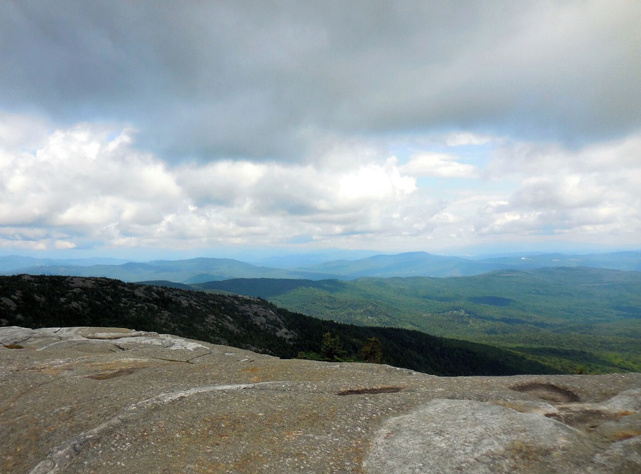 At the summit of Mt. Cardigan. A 3121 ft peak in Central New Hampshire. A moderate hike of 1.5 miles from the parking lot on the western side of the mountain. Stunning 360 degree views off of the granite, treeless summit make this an outstanding short day hike for families. It can be warm hiking up, and quite cooler with a lot a wind at the top.