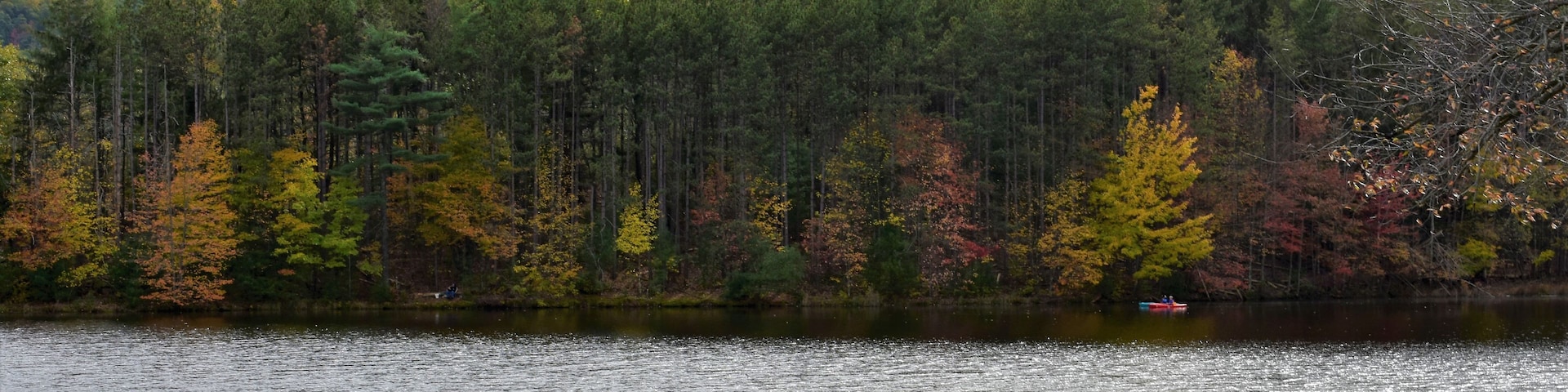 Un lago tranquilo rodeado de árboles de colores otoñales y un paisaje montañoso.