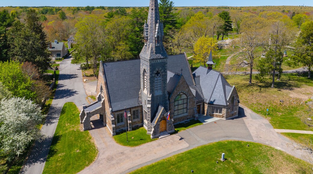 A church with a tall steeple, surrounded by trees and a clear sky.