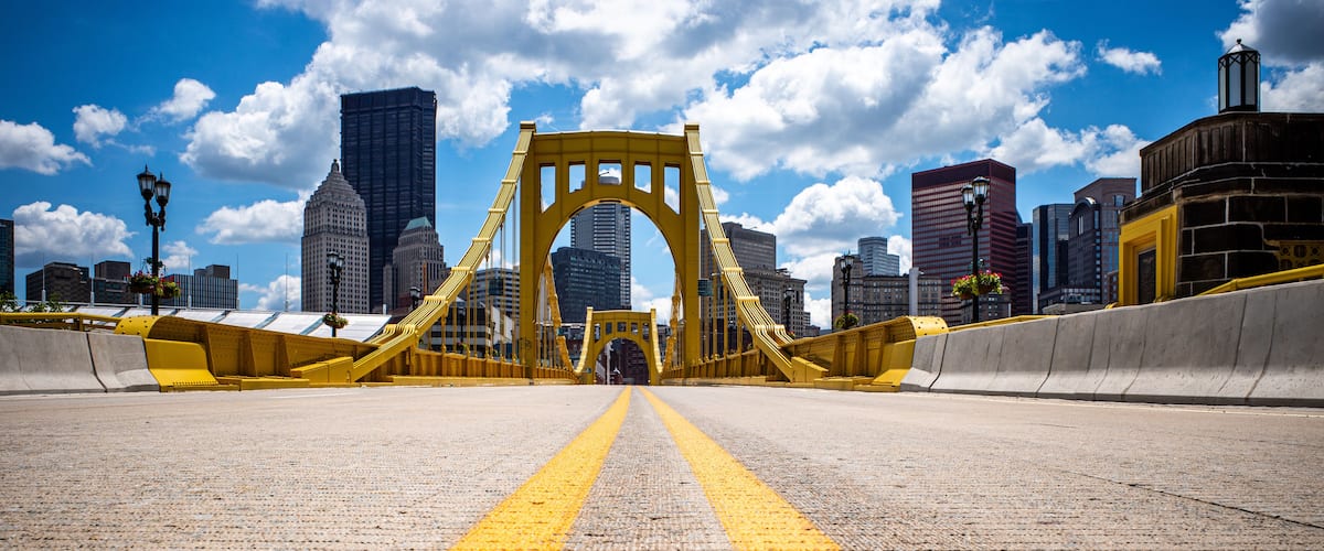 Un puente amarillo con una carretera que conduce hacia él, rodeado de edificios urbanos.