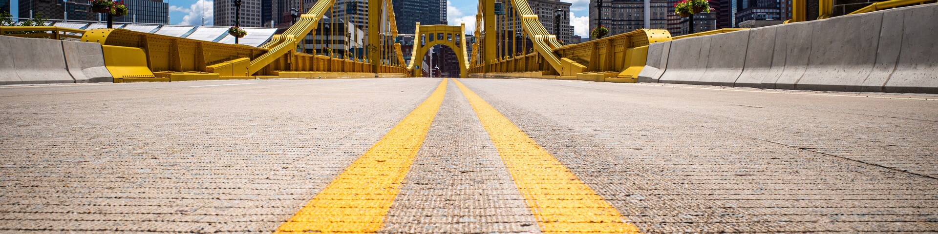 A yellow bridge with a road leading to it, surrounded by city buildings.