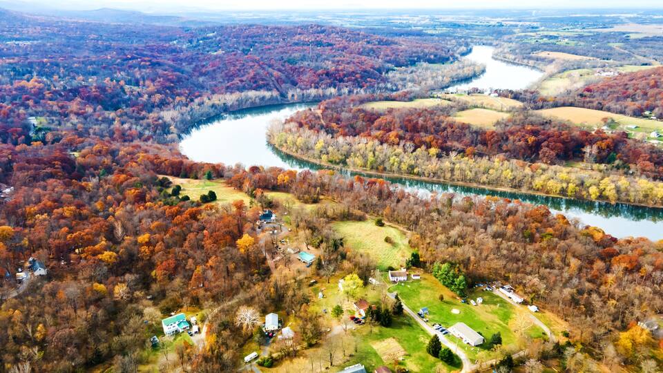 drone view of autumn forest and river bend in west virginia.
