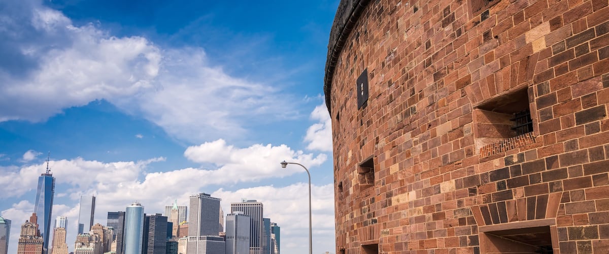 A city skyline with modern skyscrapers and a historic brick building with a clock.