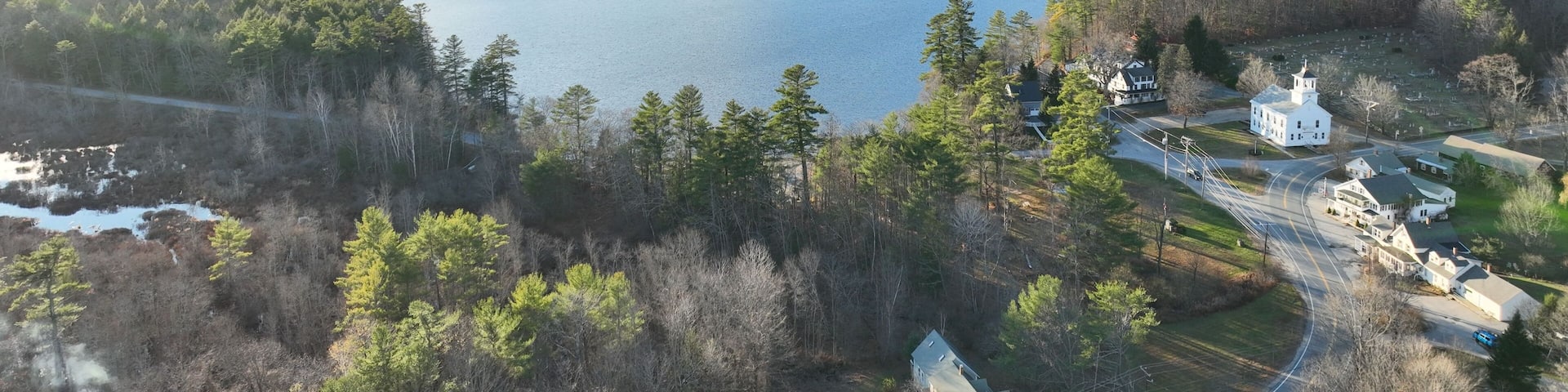 Aerial shot above Kezer Lake in Sutton New Hampshire on a sunny day with buildings around