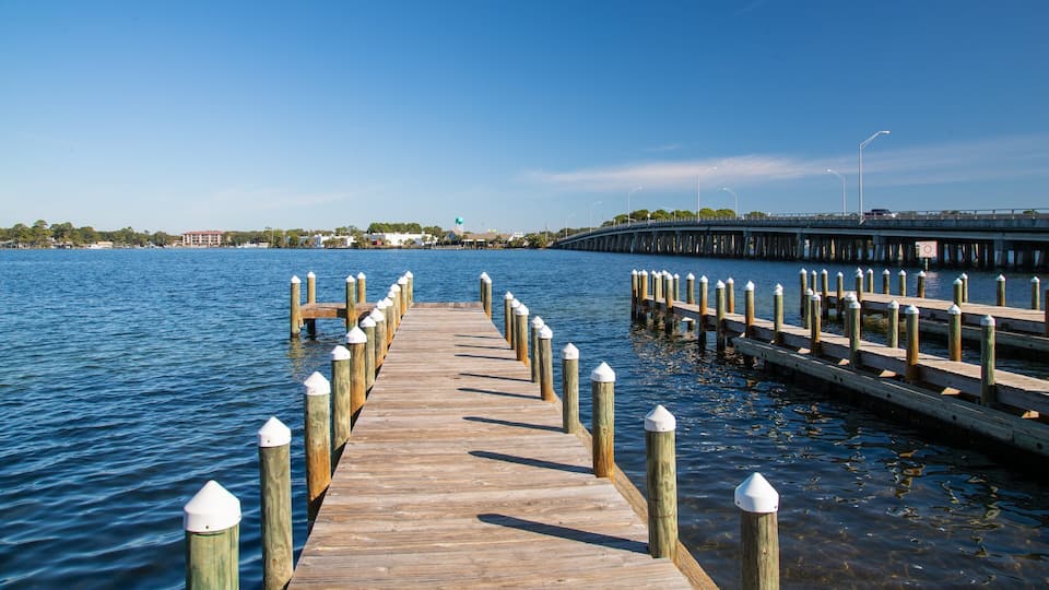 A wooden pier extending into a calm body of water with a clear sky above.