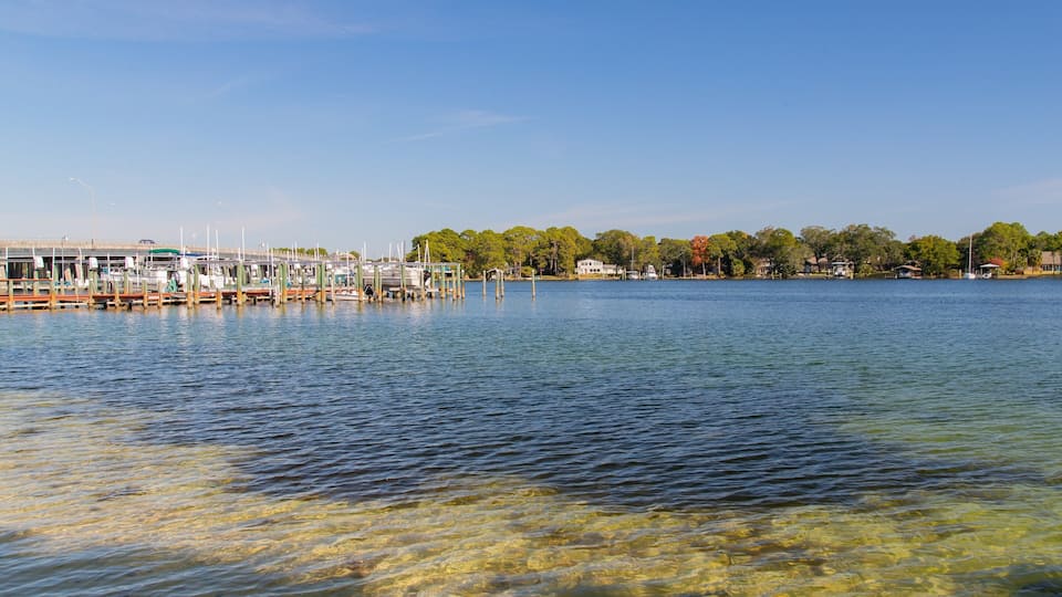 A marina with boats docked, a clear blue sky, and a calm lake.
