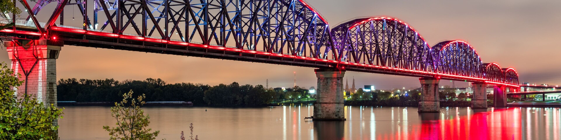 Un puente muy iluminado con varios arcos sobre un río tranquilo.