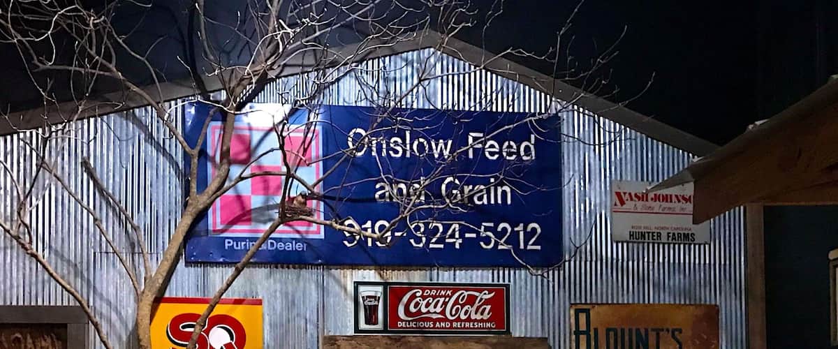 A rustic building with signs for 'Olslow Feed & Grain' and 'Hunter Farms'.