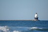 Um farol à beira-mar com ondas quebrando em primeiro plano.