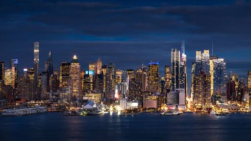 New York City panoramic view at dusk from the Hudson River. The view includes the skyscrapers of Manhattan Midtown West Manhattan illuminated at night. NYC, NY, USA