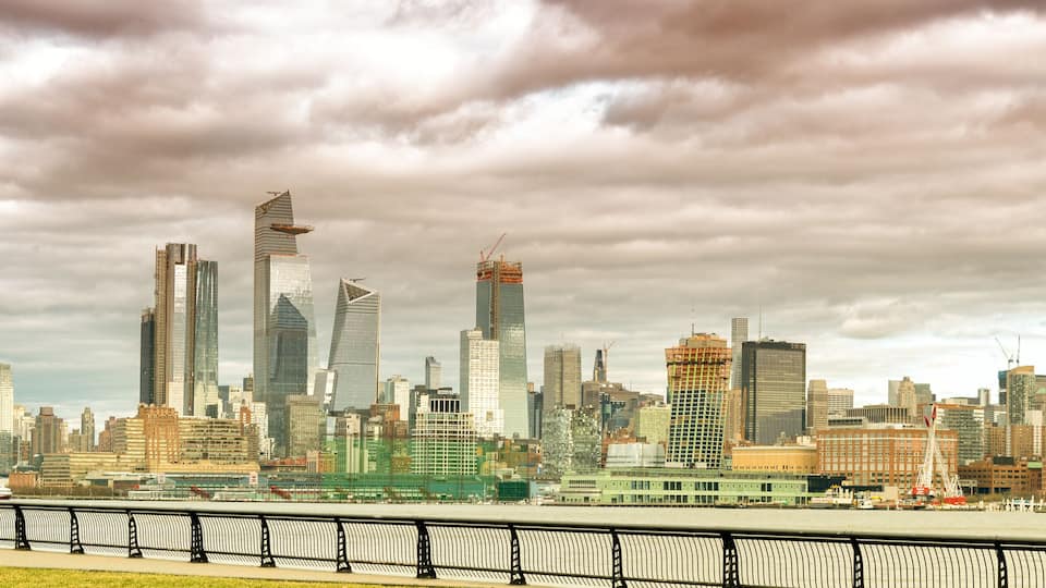 A city skyline with modern skyscrapers and a river in the foreground.