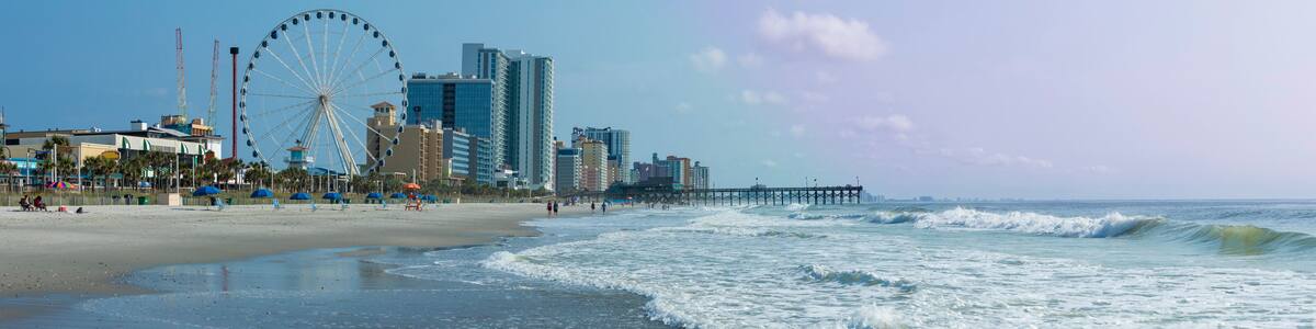 Panoramic view of Myrtle Beach, South Carolina with beach, hotels, ferris wheel, and boardwalk.