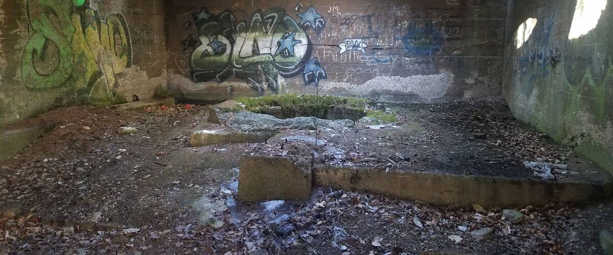 An abandoned building with graffiti on the walls and a circular skylight.