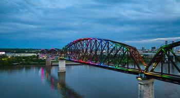 Un pont d’acier illuminé de lumières colorées qui se reflètent sur l’eau.