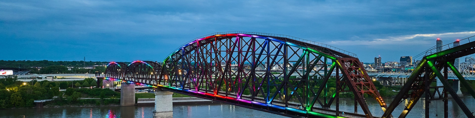 Eine Stahlbrücke mit bunten Lichtern, die sich im Wasser spiegeln.