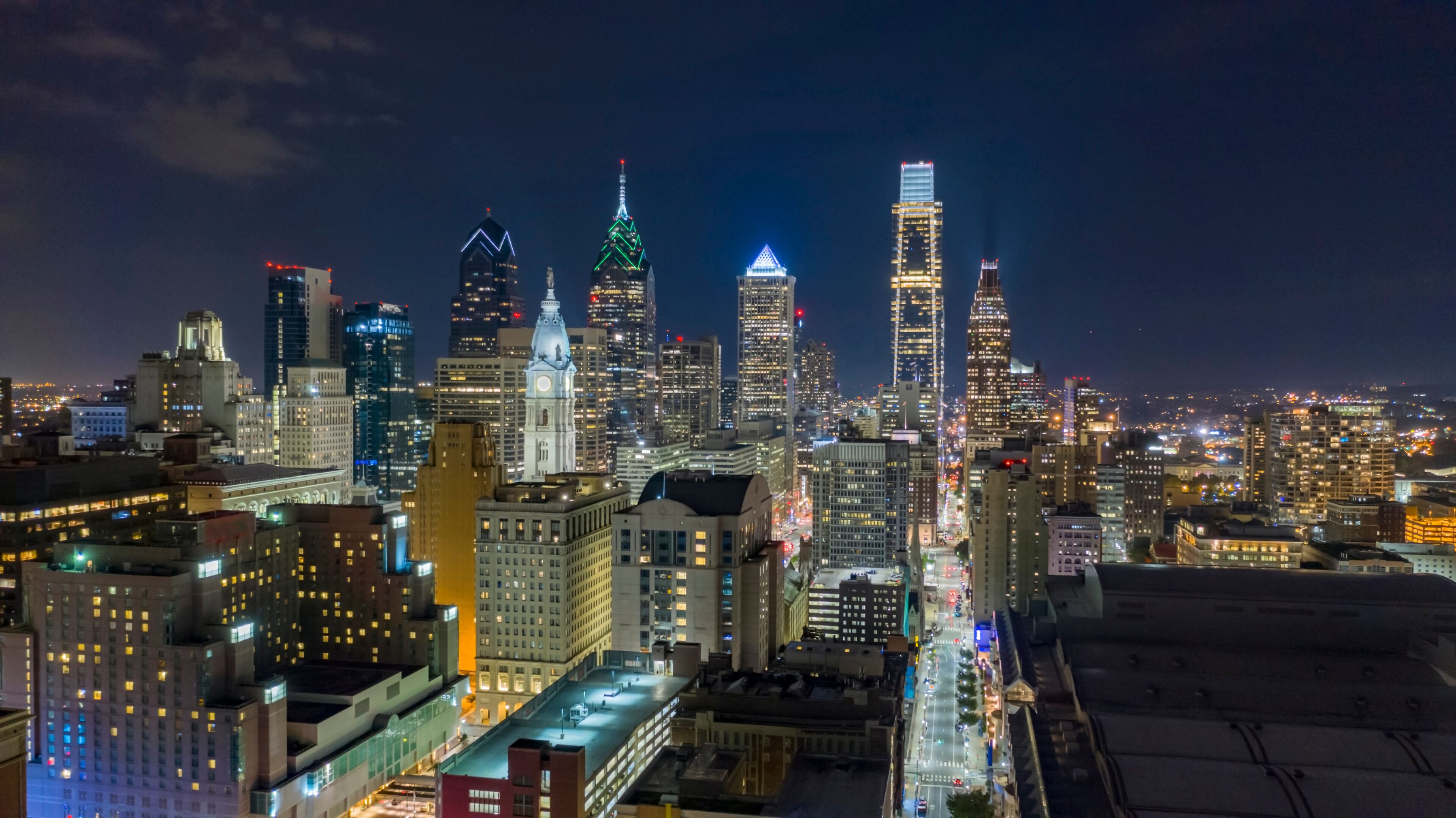 A nighttime cityscape with illuminated skyscrapers and a dense urban layout.