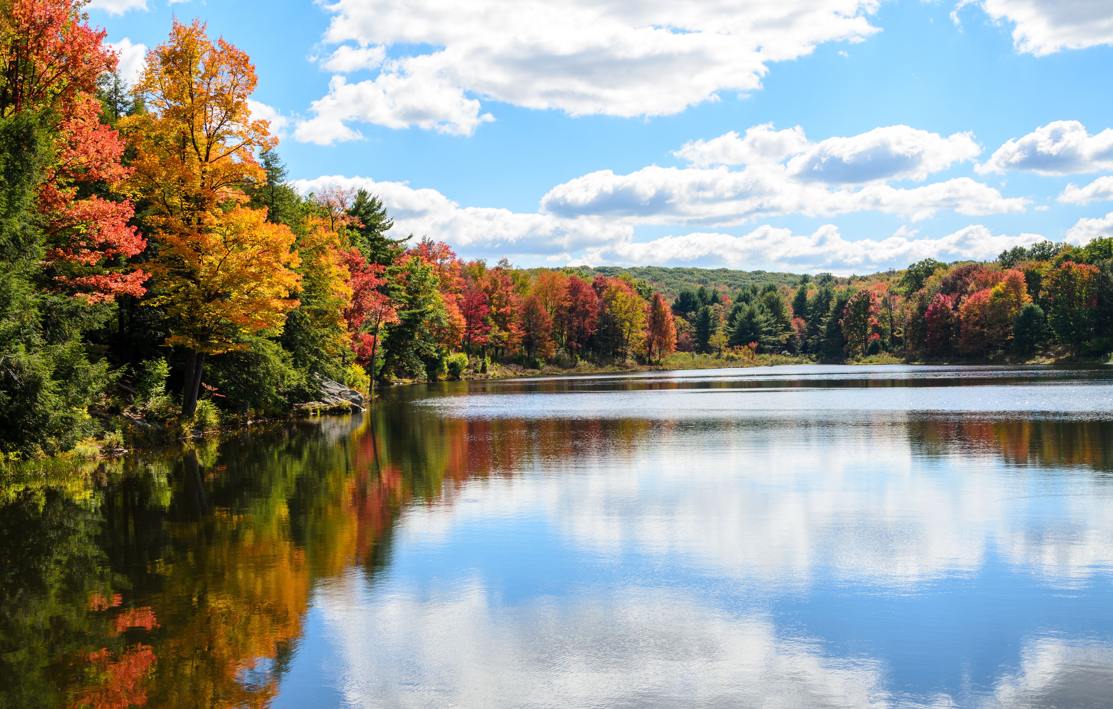 A calm lake surrounded by autumn-colored trees reflecting in the water.