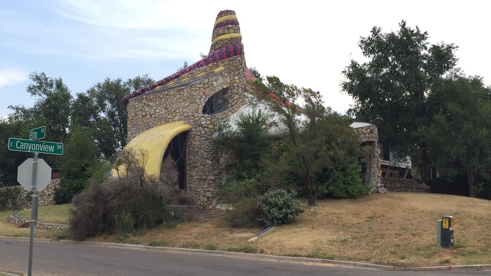 A stone building with a colorful roof and a yellow awning.