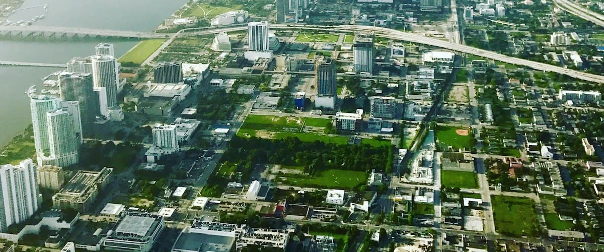 An aerial view of a city with a river, high-rise buildings, and green spaces.