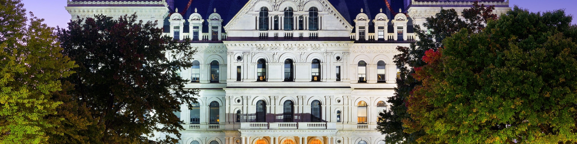 Um edifício grande e ornamentado, com várias torres e uma estátua em primeiro plano.