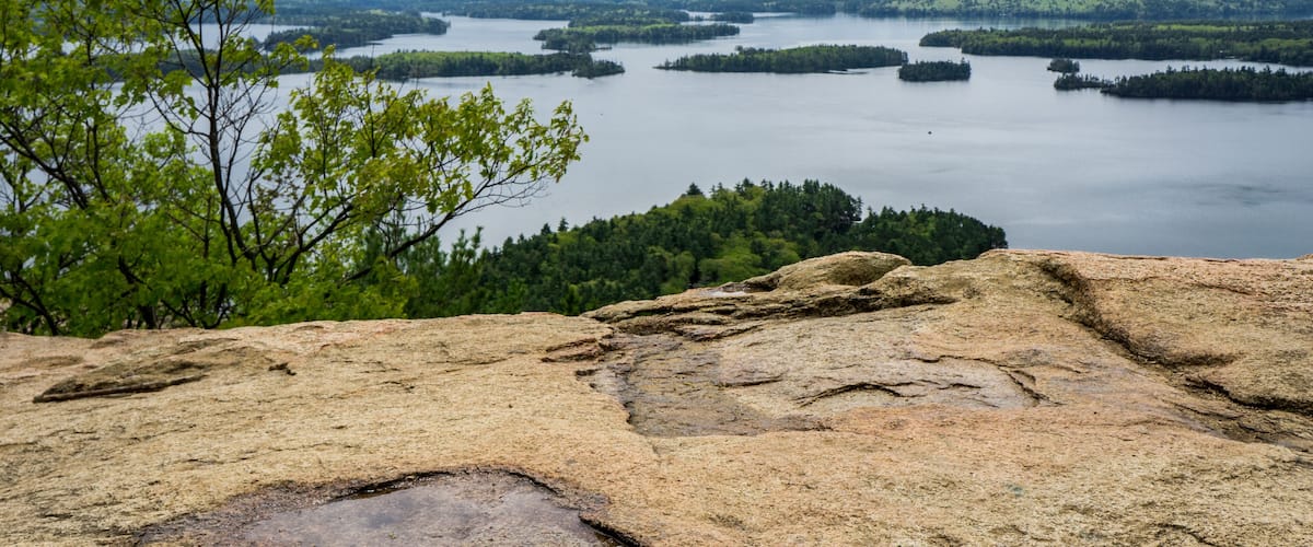 A lake surrounded by forested hills and rocky terrain.