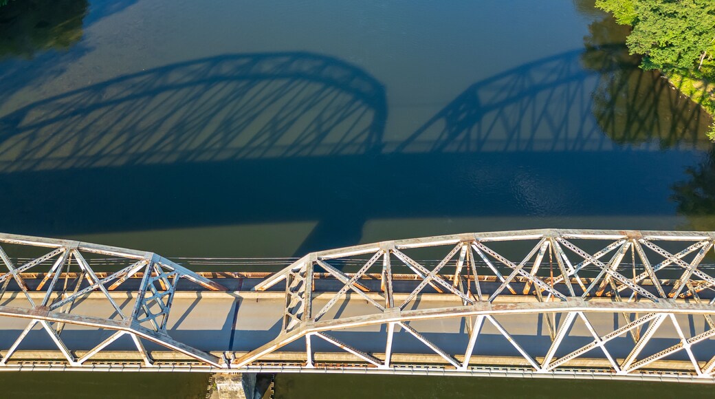 Un pont en acier à structure en treillis, enjambant une étendue d’eau.