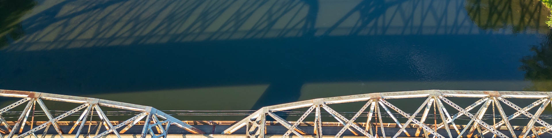 Eine Stahlbrücke mit Fachwerkkonstruktion über einem Gewässer.