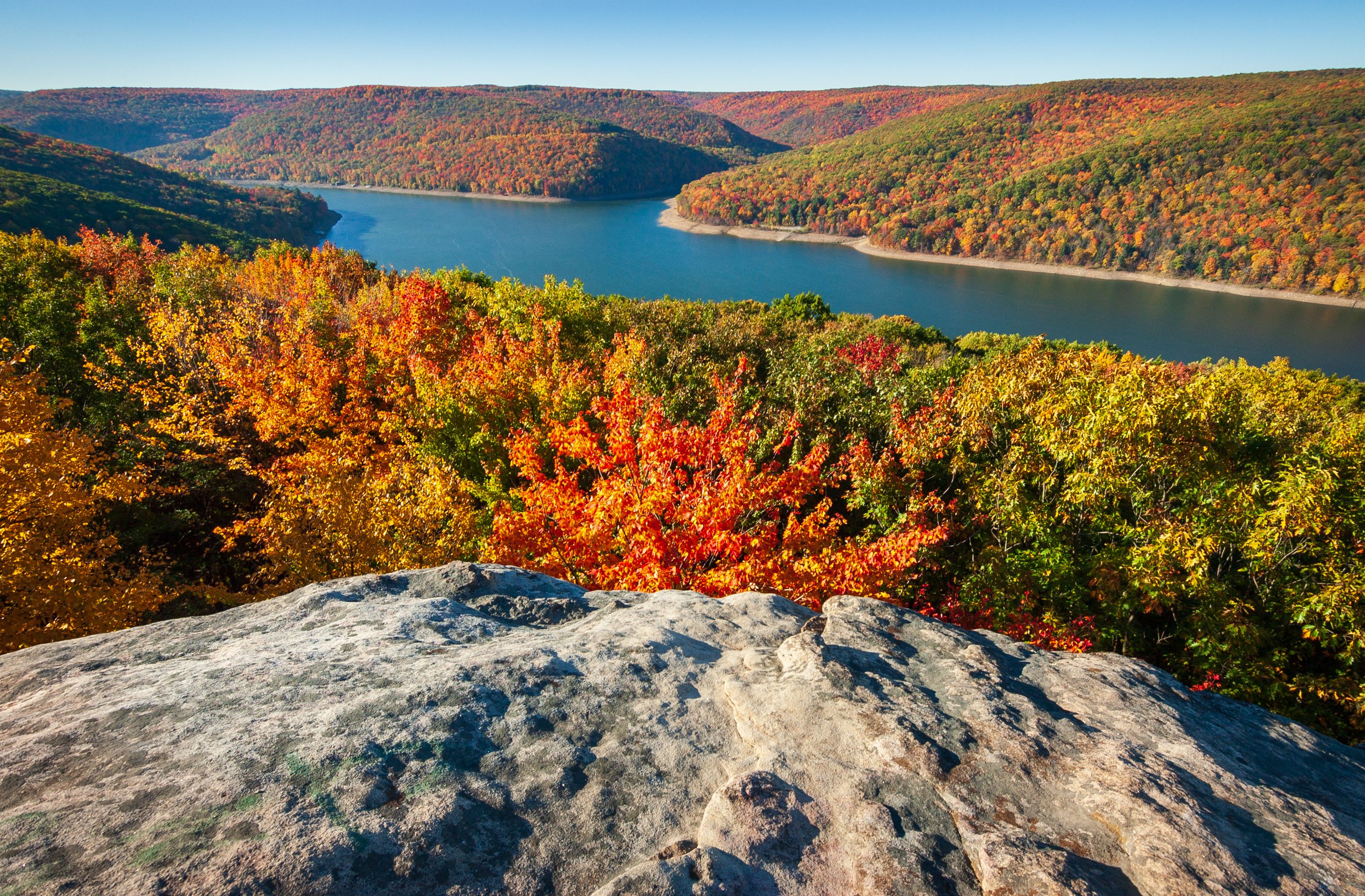 A mountainous landscape with autumn foliage and a lake.