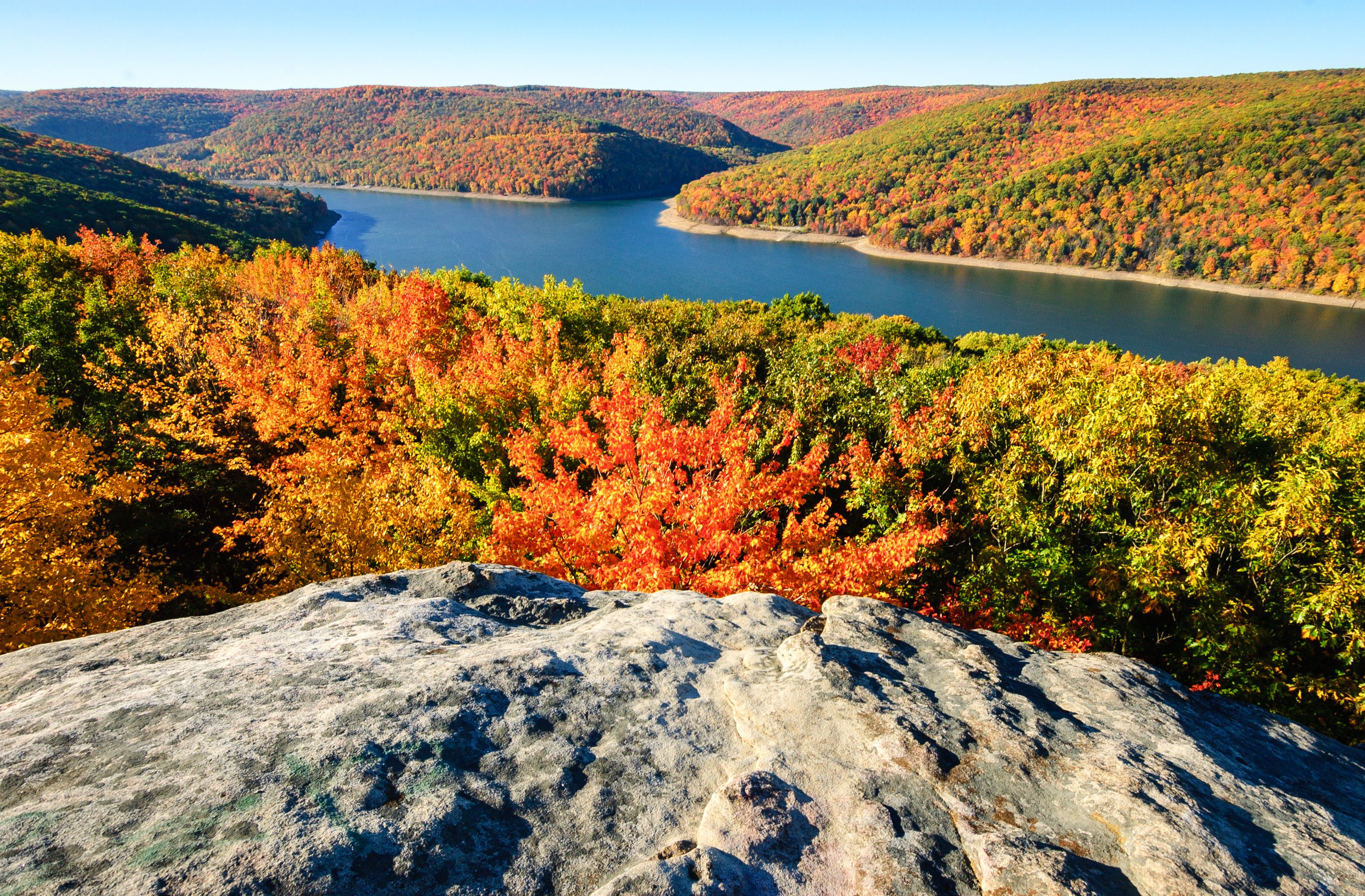 A mountainous landscape with autumn foliage and a lake.
