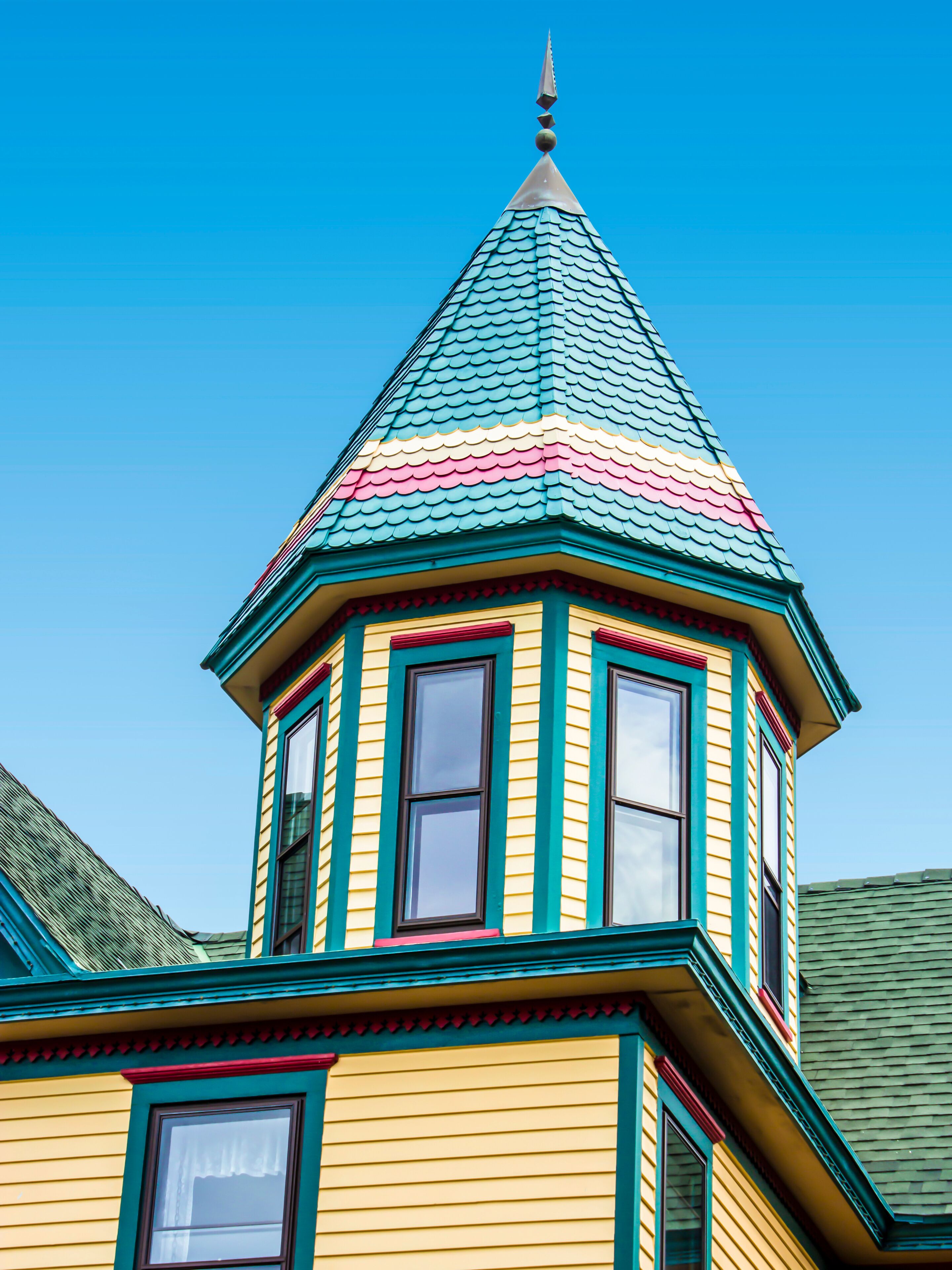 A colorful Victorian-style tower with a green roof and pink trim.