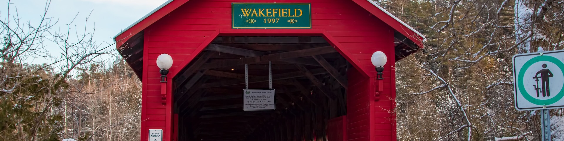 Red wood covered bridge on a bright winter afternoon - Gendron Covered Bridge, Wakefield, Quebec, Canada