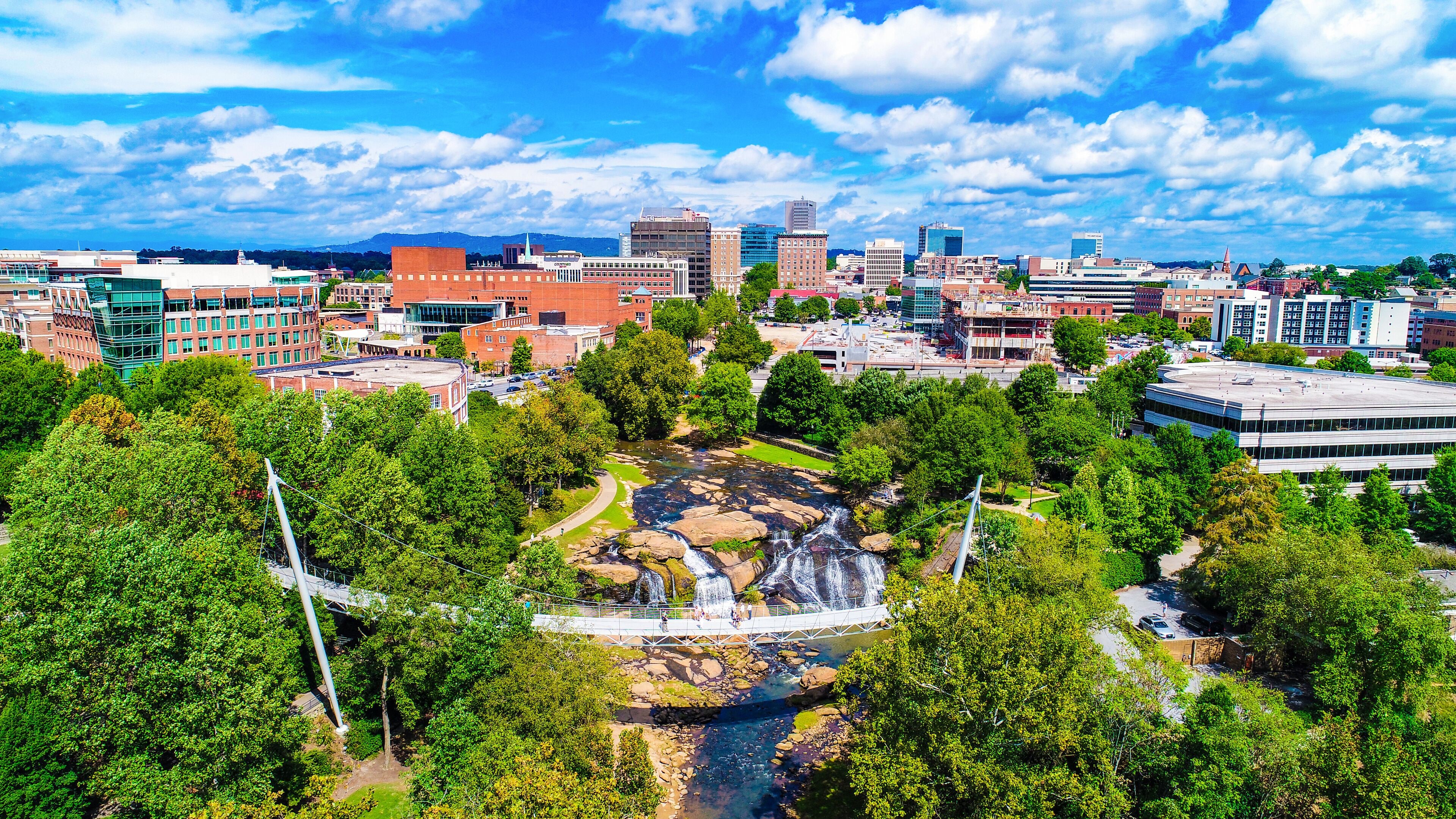 A cityscape with a waterfall, green trees, and modern buildings.