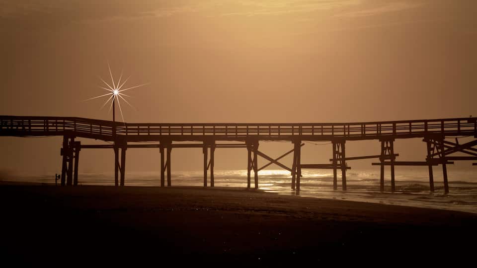 A pier extending into the ocean at sunset.