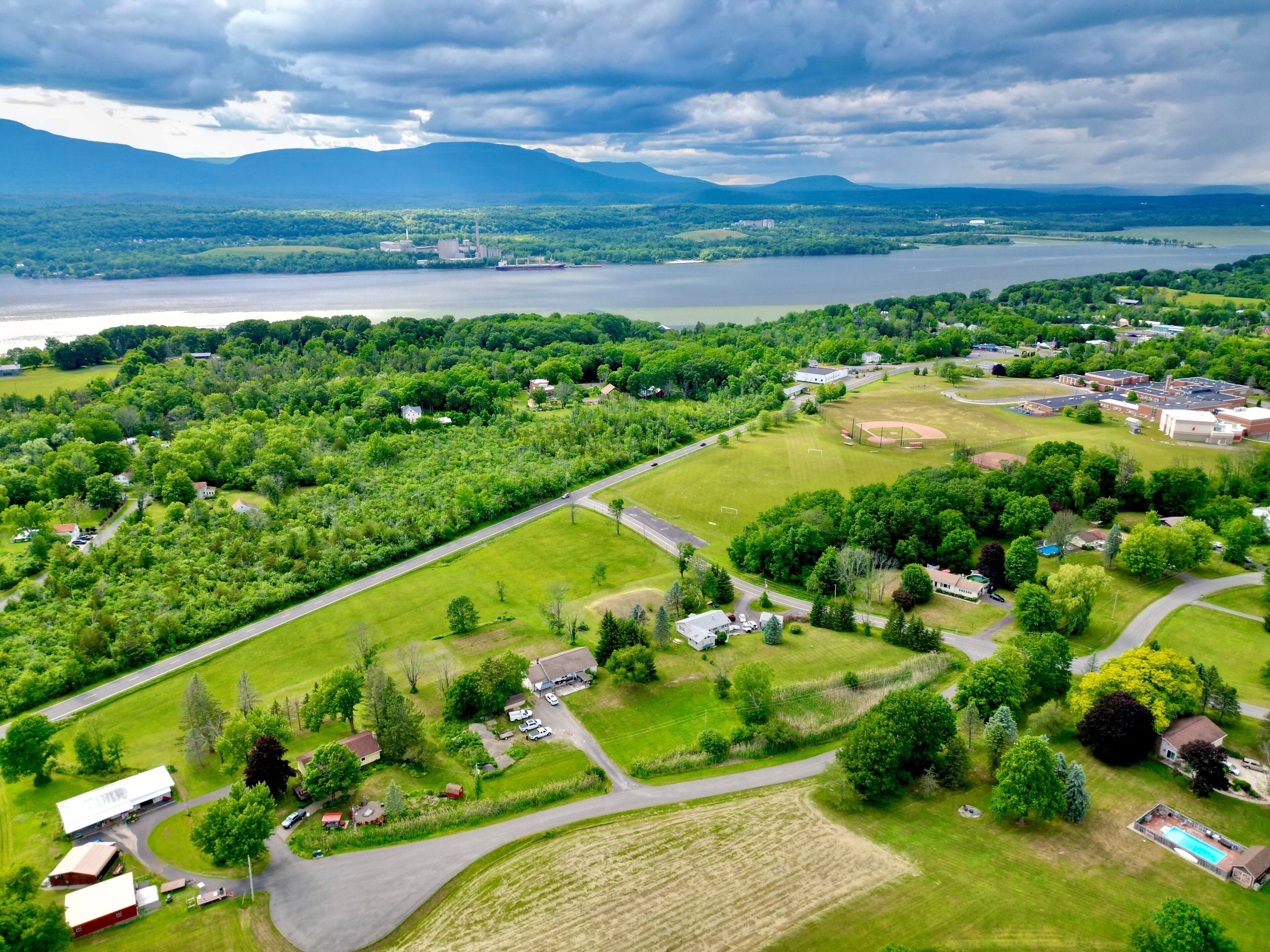 A lush green landscape with a lake, a baseball field, and residential houses.