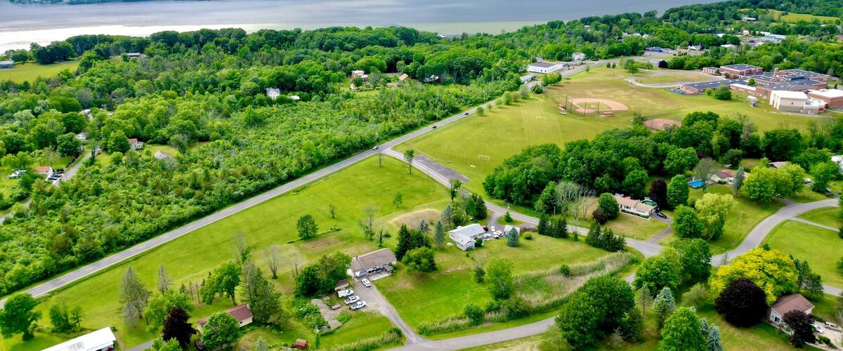 A lush green landscape with a lake, a baseball field, and residential houses.