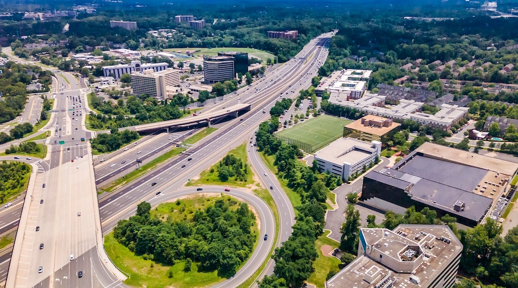 Eine mehrspurige Autobahnkreuzung mit angrenzender Stadtentwicklung und Grünflächen.